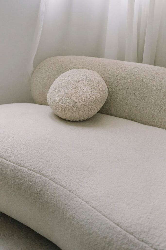 الجمال للأثاث ( ورشة ربيع احمد نعيم ) Stylish cream sofa with a round cushion, perfect for modern living spaces.